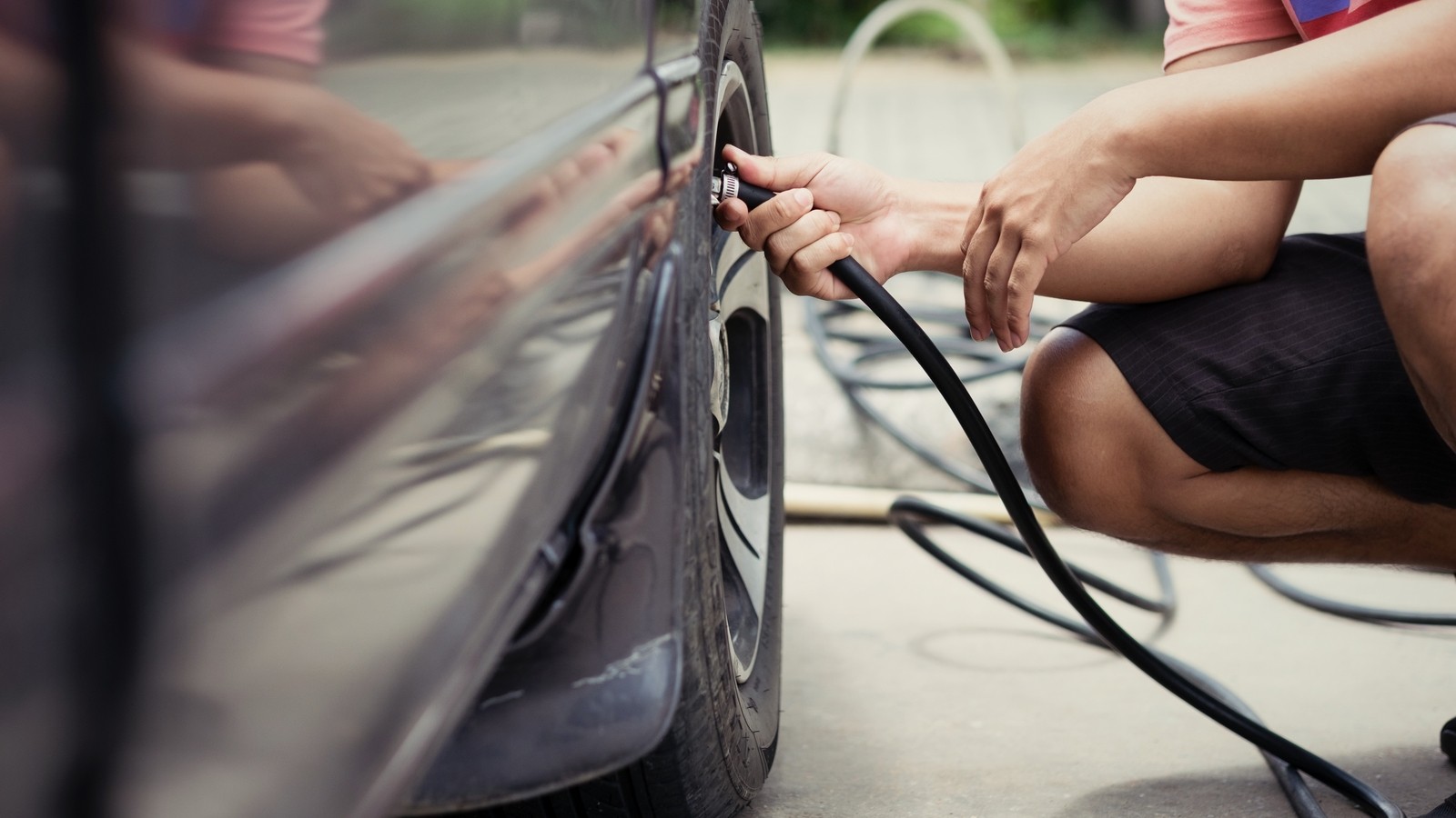 Man driver checking air pressure and filling air in the tires of